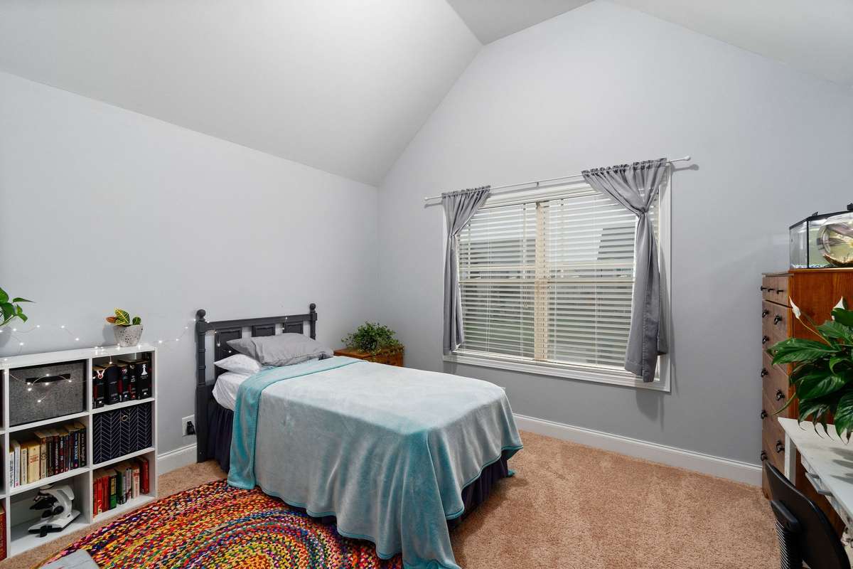 Well-sized secondary bedroom with a vaulted ceiling, window with natural light, and plush new carpet throughout, ready to accommodate family members or guests comfortably.