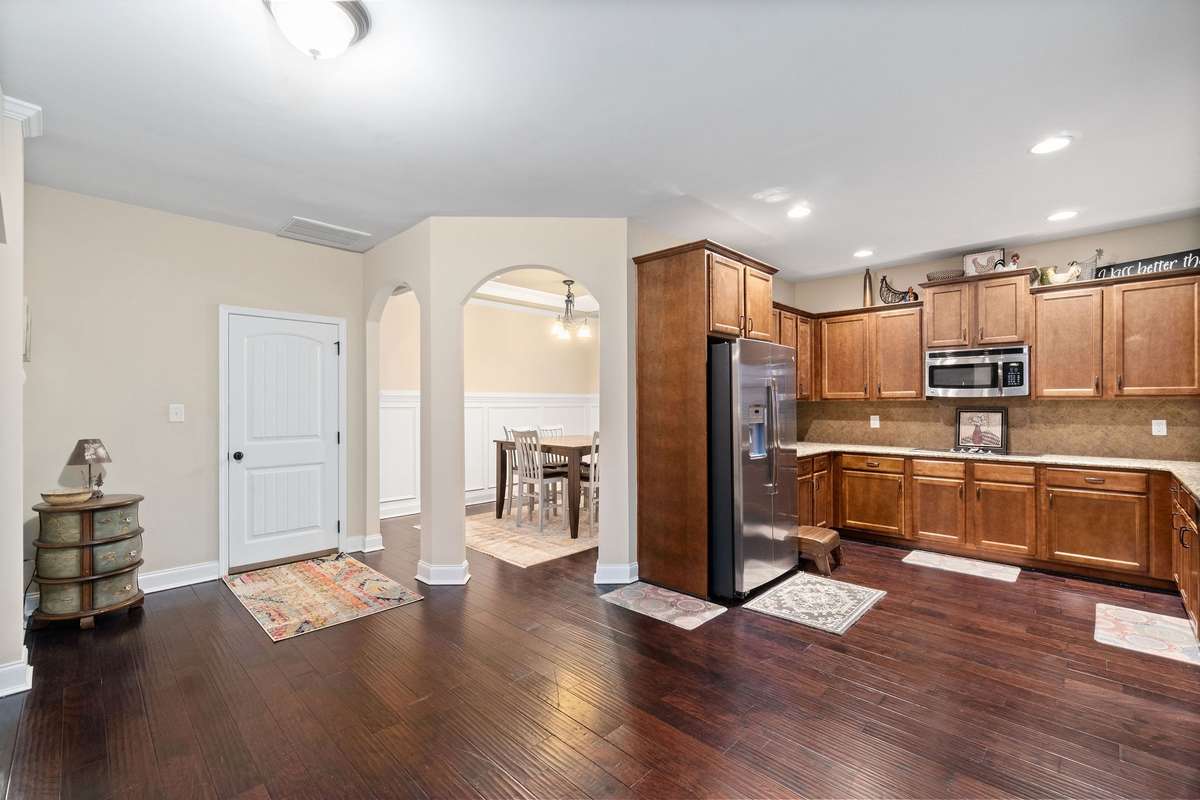 Open-concept main level showcasing the seamless flow between the living area, kitchen, and entry hall, with gleaming hardwood floors and arched architectural details throughout.
