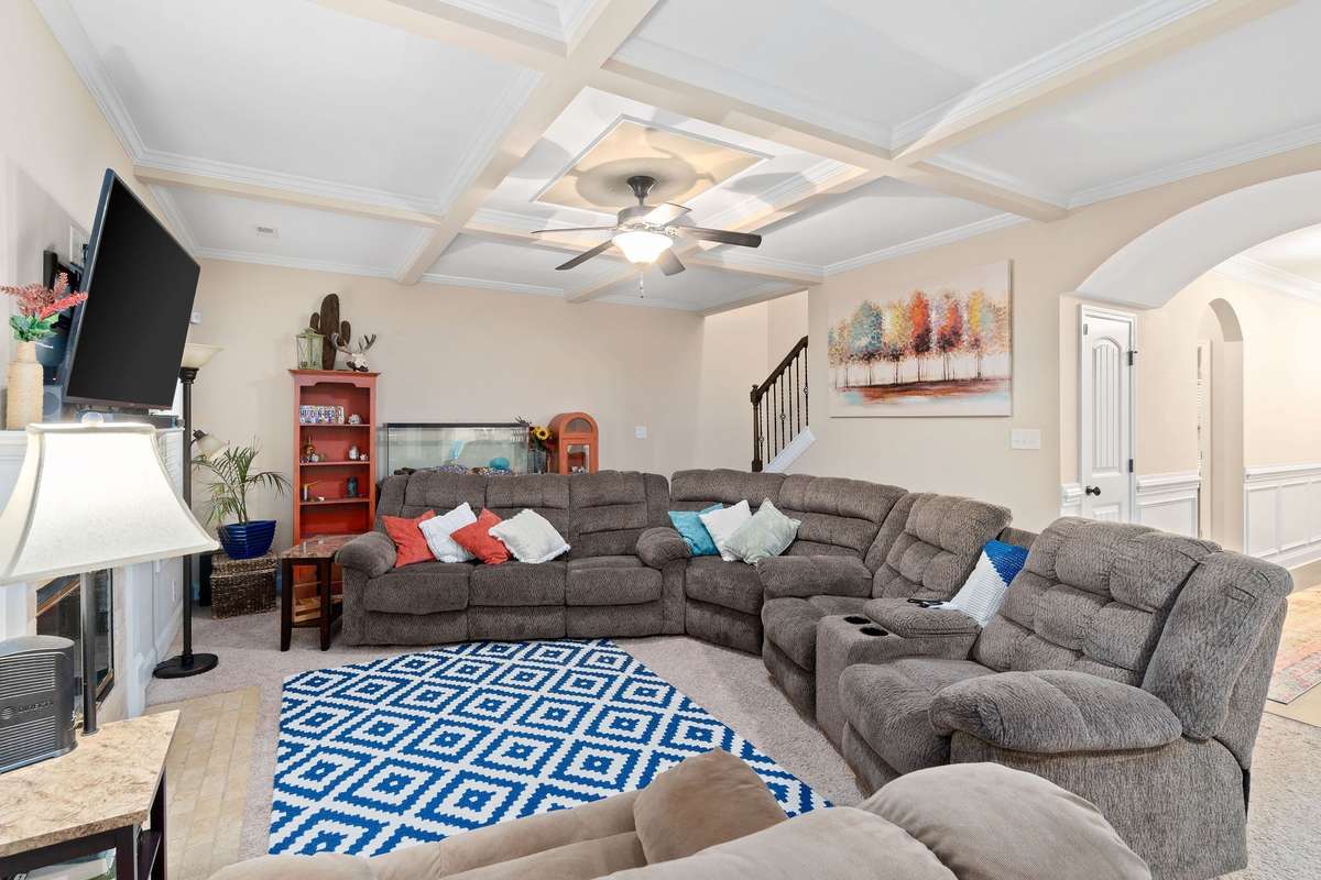 Additional dining room view highlighting the intricate coffered ceiling detail, neutral warm tones, crisp white wainscoting panels, and beautiful dark hardwood flooring.