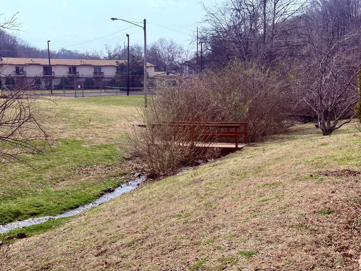 Bridge over neighborhood creek leads to walking path and neighborhood amenities such as laundry area and pool.