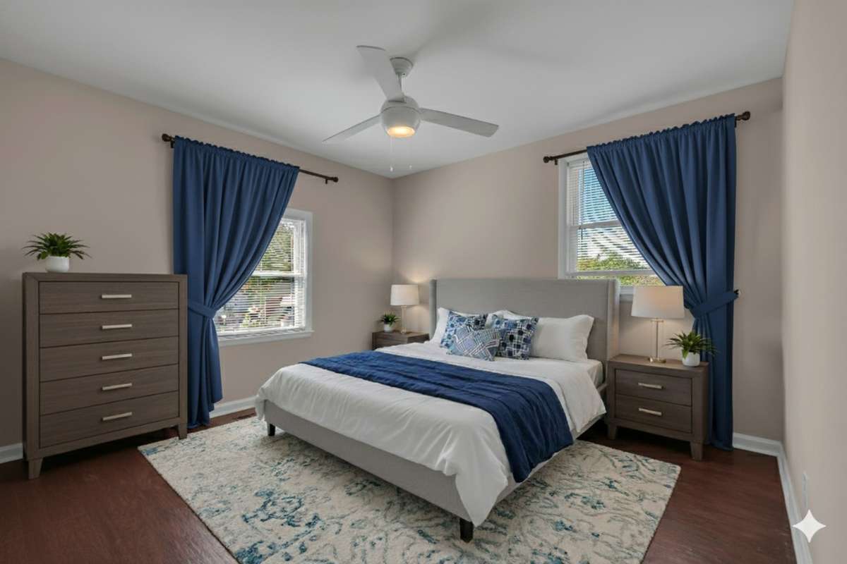 Spacious primary retreat with double windows, ceiling fan, and rich flooring—staged to show easy comfort and style.