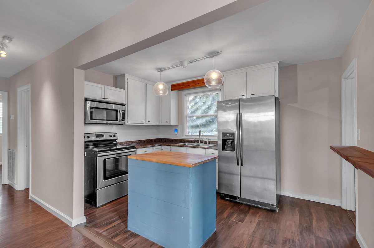 Updated kitchen with stainless appliances, butcher-block island, and pendant lighting for a modern touch.
