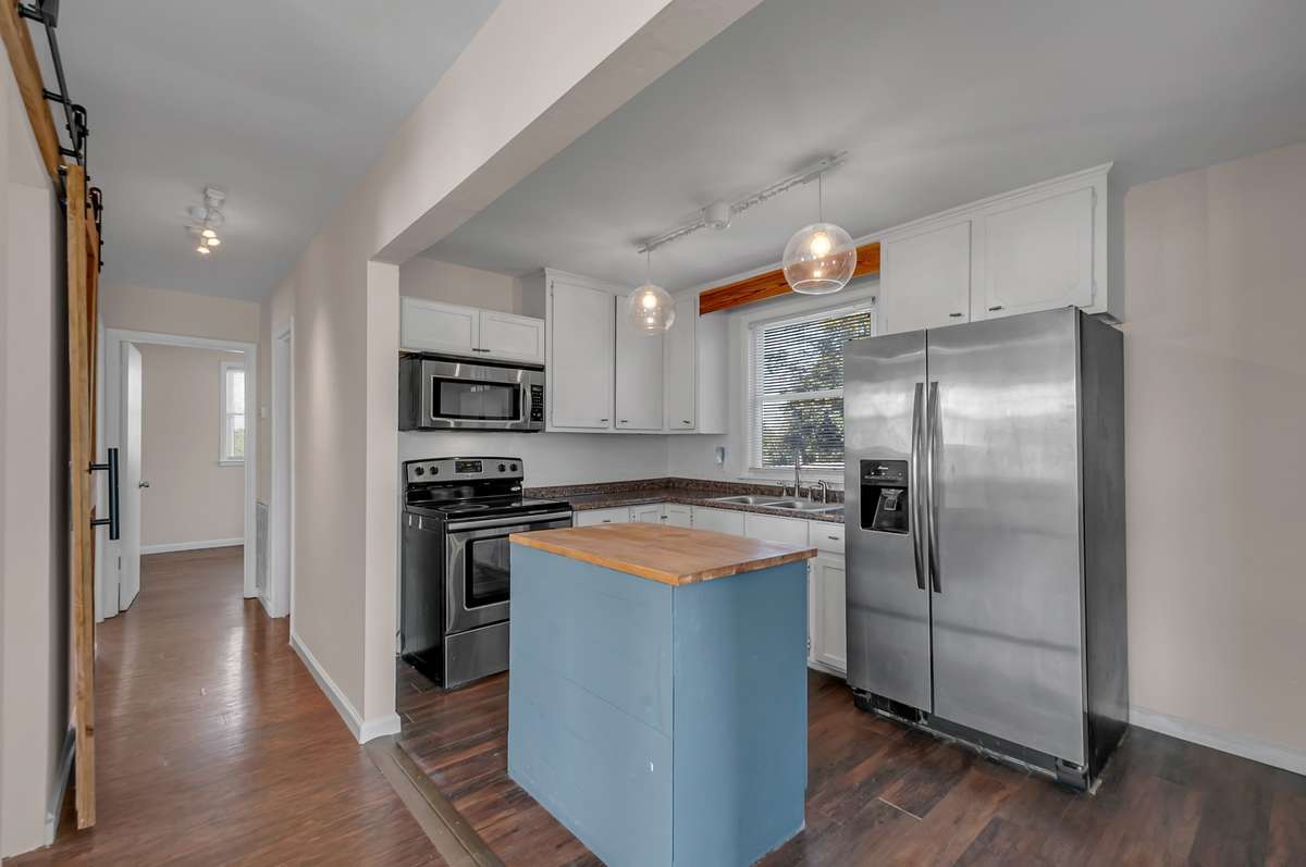 Open layout connects kitchen and living spaces, highlighted by a sliding barn door and custom touches.