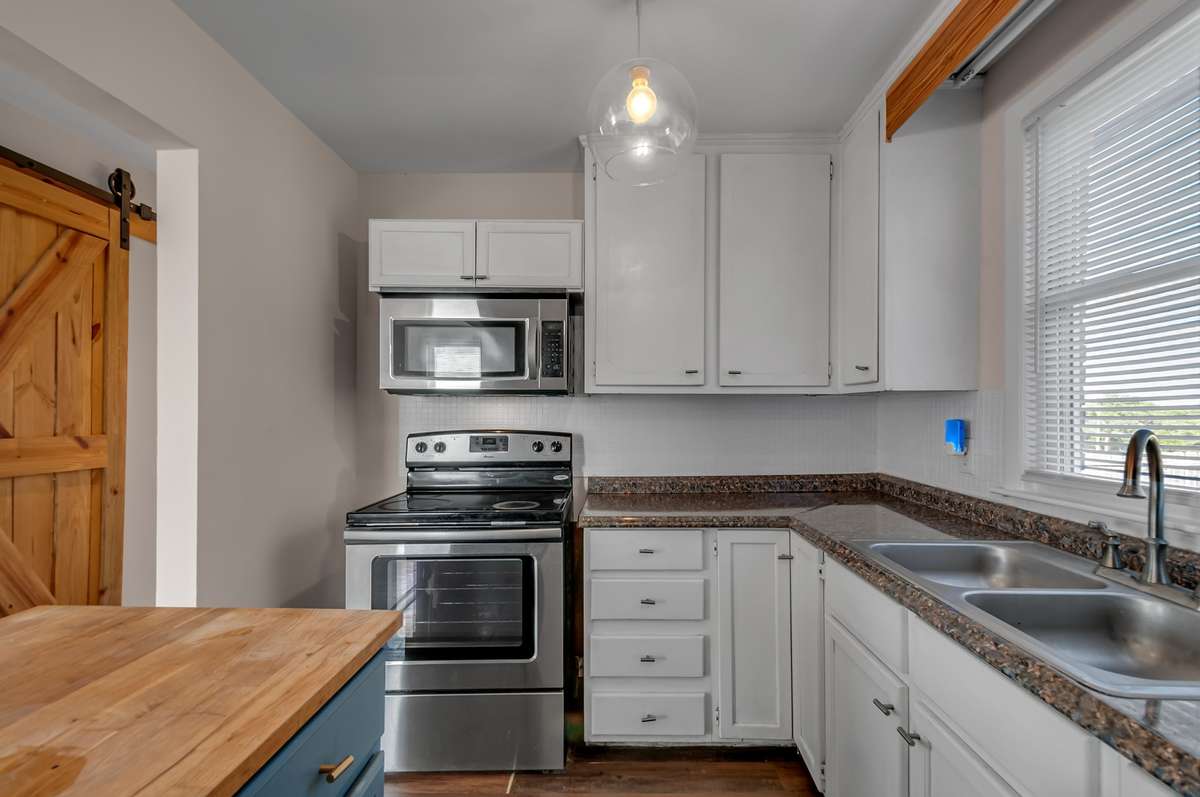 Sleek stainless steel range and microwave pair with ample cabinetry and window light.
