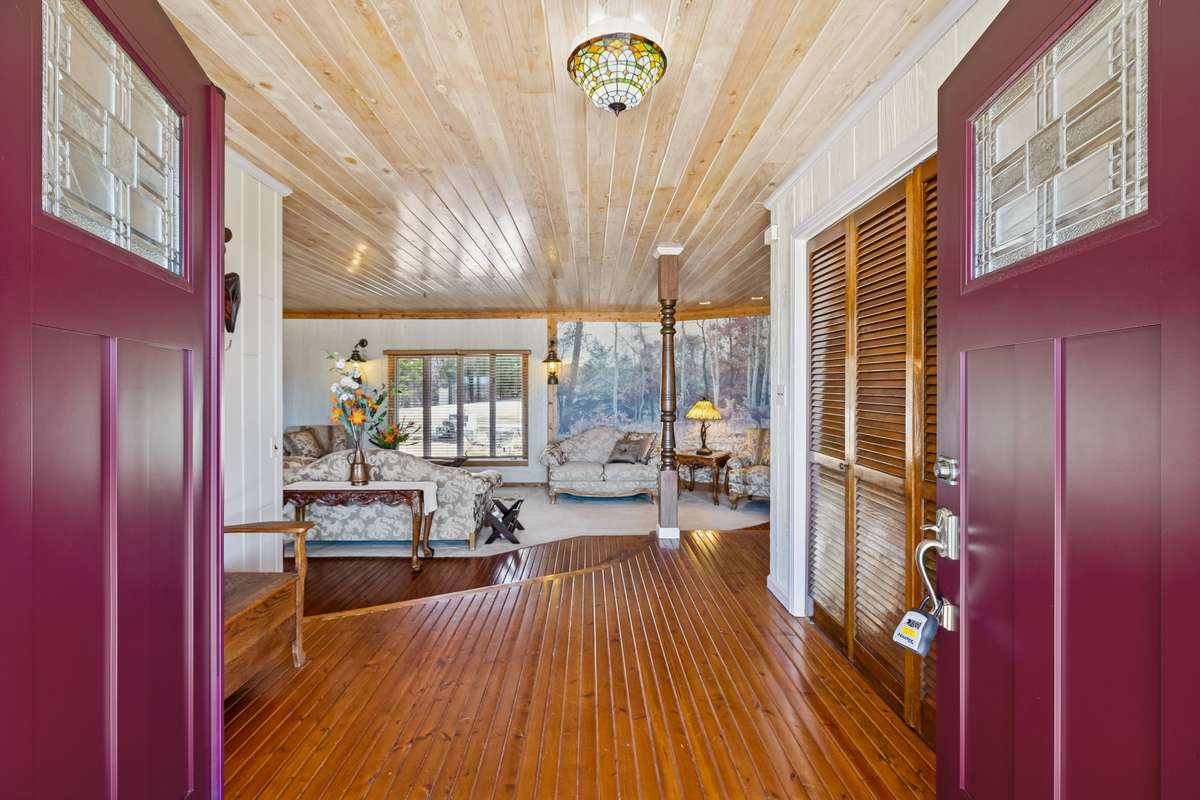 Inviting entry featuring double front doors, warm wood flooring, and a tongue-in-groove, wood ceiling that sets the tone for this spacious one-level home! 1372 Short Mountain Rd, McMinnville, TN 37110