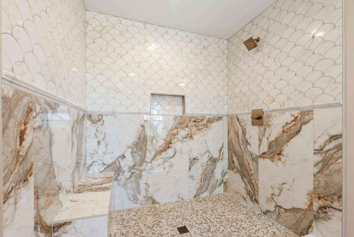Custom walk-in shower with dramatic floor-to-ceiling tile, pebble flooring, built-in bench, shampoo niche, and high-end fixtures—designed for a true spa experience! 510 Iris Avenue, Murfreesboro, TN 37128