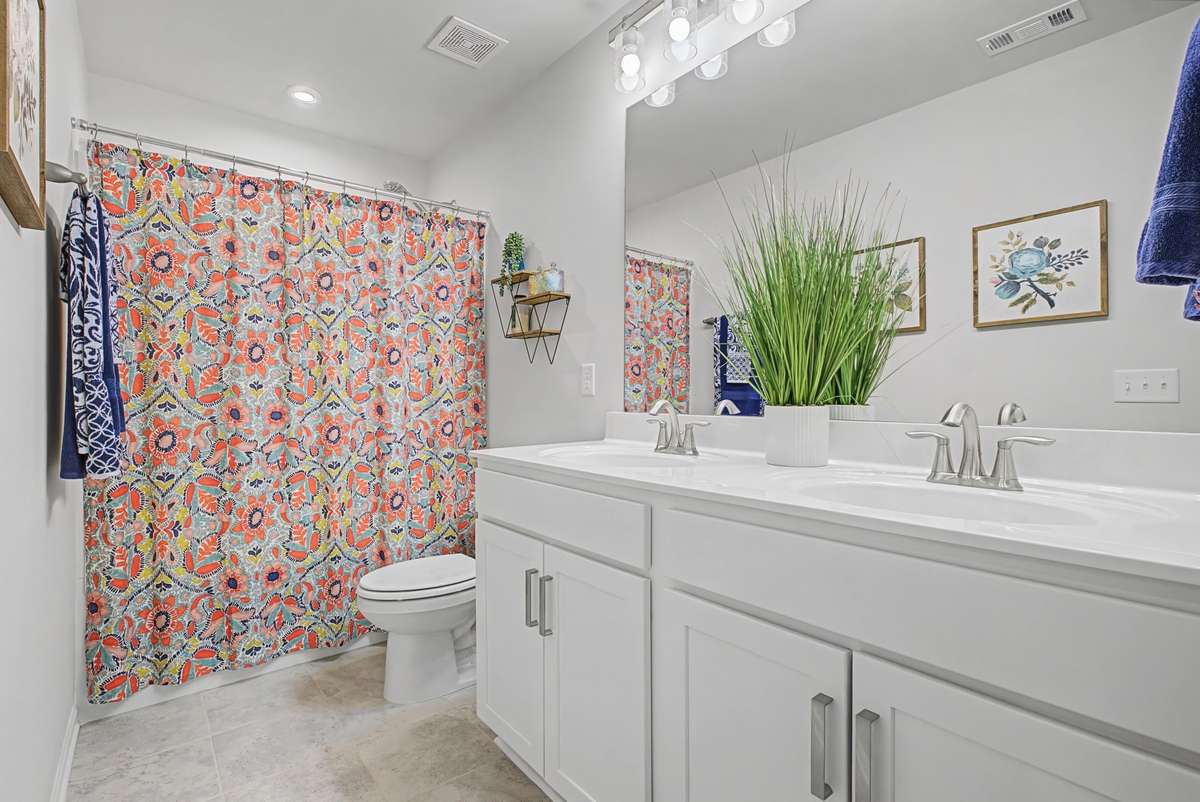 The spacious secondary bathroom features double vanities and a convenient shower and tub combination perfect for confort and functionality.