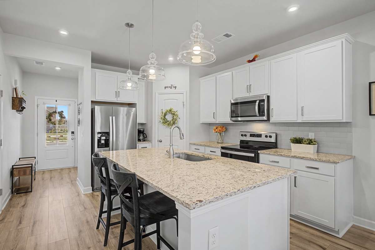 The gorgeous kitchen features s stunning island, granite countertops, a stylish backsplash and stainless steel appliances.