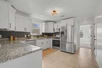 Kitchen featuring granite countertops, modern backsplash, white cabinets with soft close doors and drawers, black hardware, stainless steel appliances