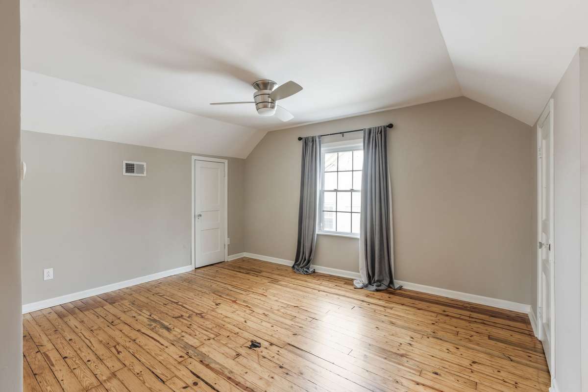 The spacious primary suite with original flooring has so much potential!