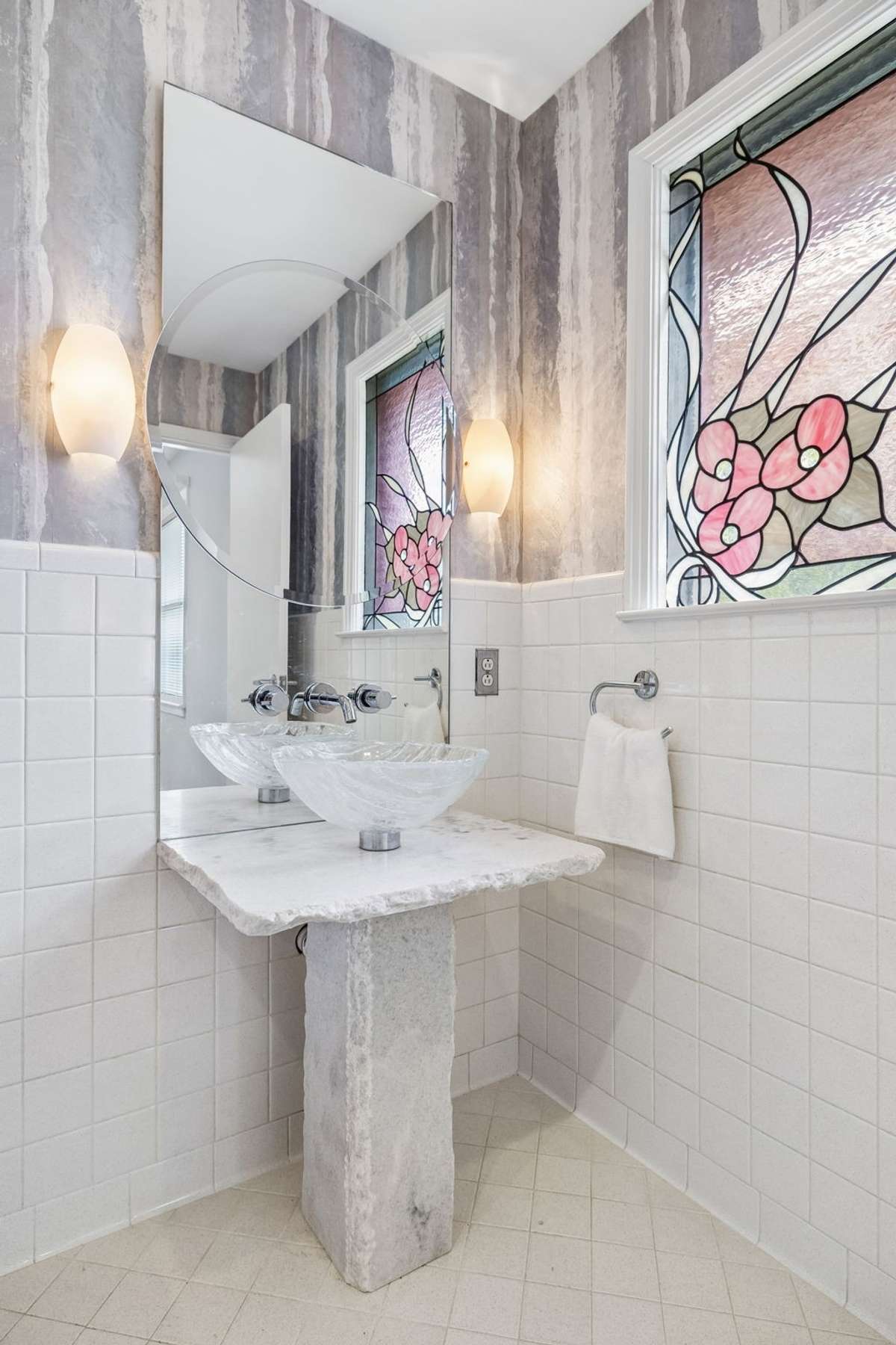 Full bath with shower/tub combo. Custom marble pedestal with glass vessel sink. Hand made designer stained glass window.