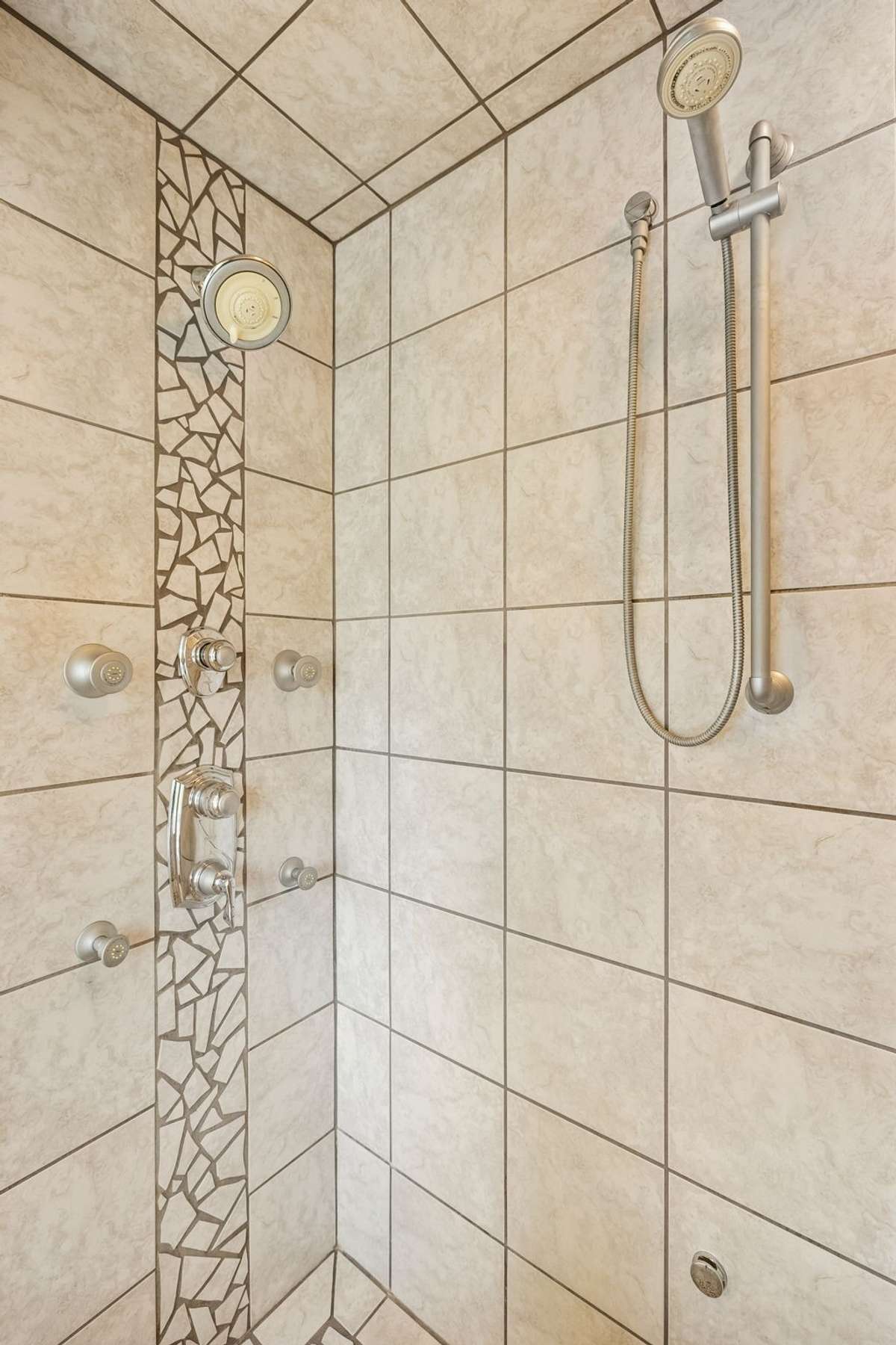 Custom mosaic shower with Multi function shower system, with four jetted body sprays, hand held shower, rain shower head and adjustable wall shower head. Also piped for Mr Steam  steam shower system
