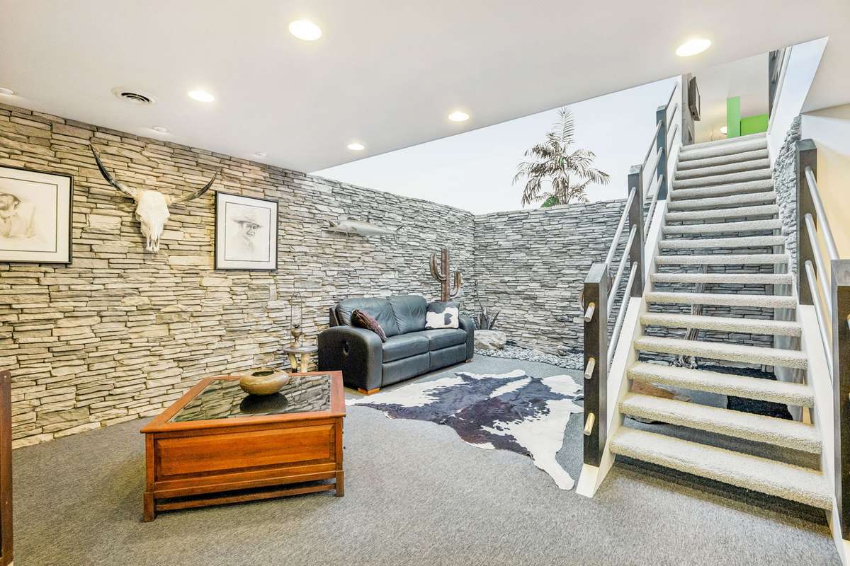 Lower level . Stacked stone surrounded area with 16' high ceiling and skylights. Stairs have open see thru treads.