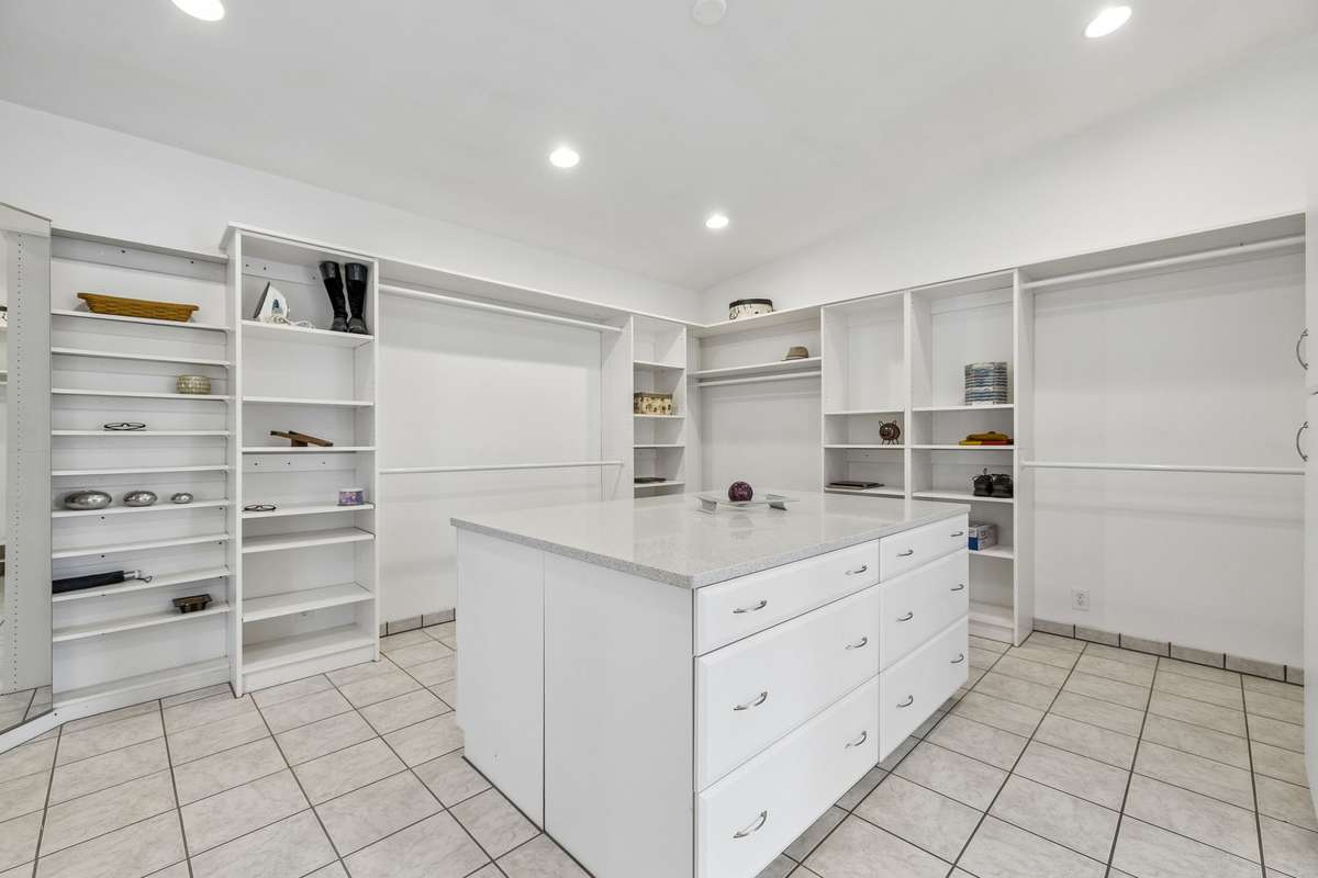 14x16 oversized designer closet with a 4x6 built in 12 drawer cabinet. Silestone single slab countertop. Additional shelving and hanging rods.