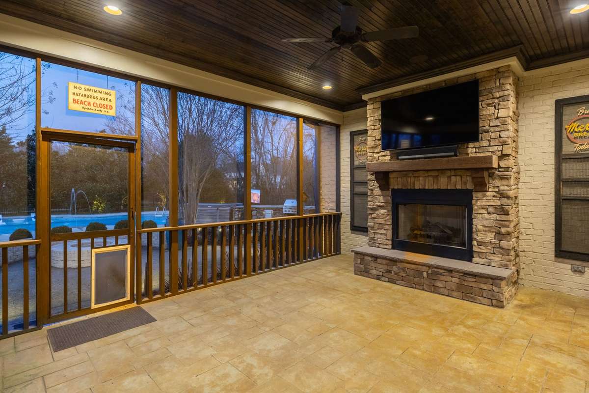 Screened in porch with stone fireplace, wood ceiling, and tile