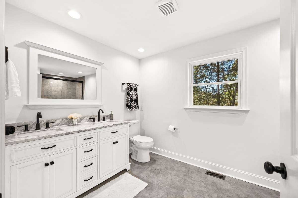 This large guest bath has double sinks, new faucets, new mirror, new tiled floors and new commode.