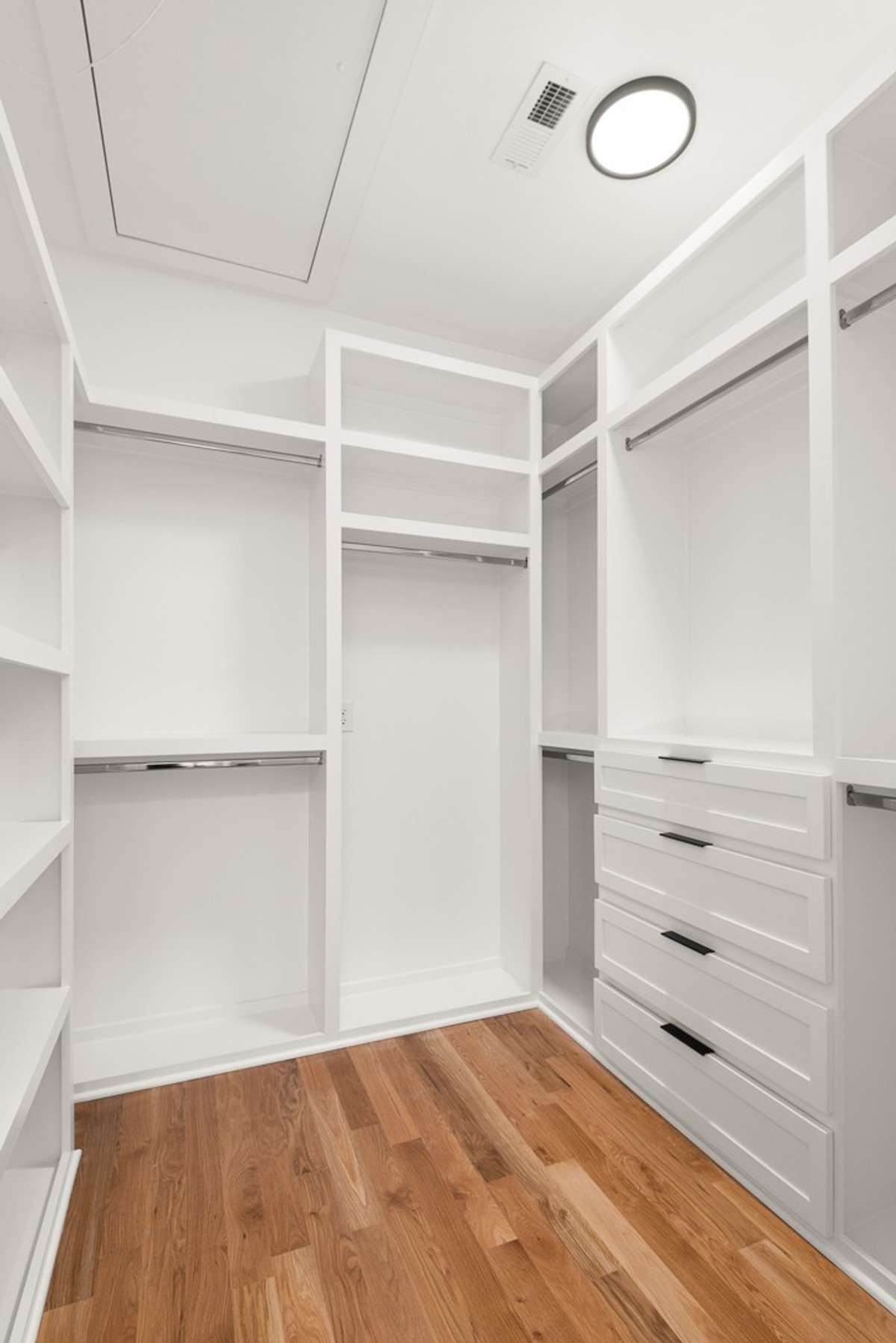 One of two custom walk-in closets in the primary suite, featuring ample storage and generous long-hanging space.