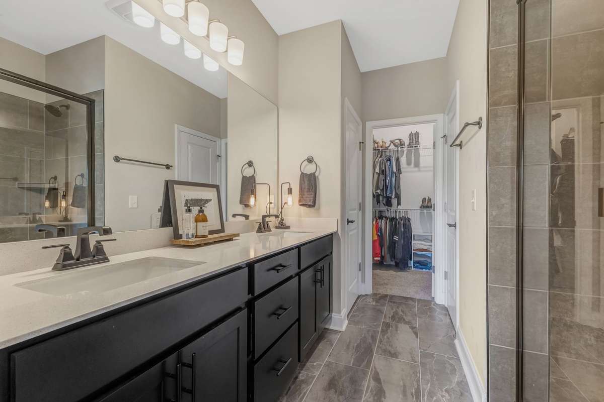 primary bathroom with dual sinks, private lavatory, tiled shower, linen closet and 2nd owners walk in closet