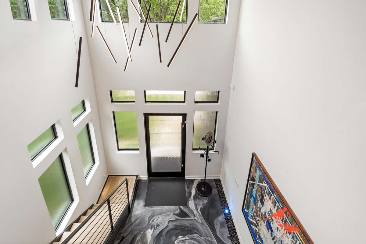 The curated architectural design starts with a solid steel floating staircase, an artistic foyer floor illuminated by accent lighting, and a captivating chandelier