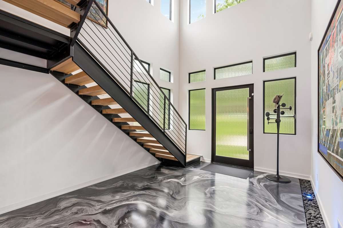The sleek contemporary design of this 5BR/5.2BA home is enhanced by an open flowing floorplan with 12'+ soaring ceilings, an abundance of natural light, and chic statement lighting