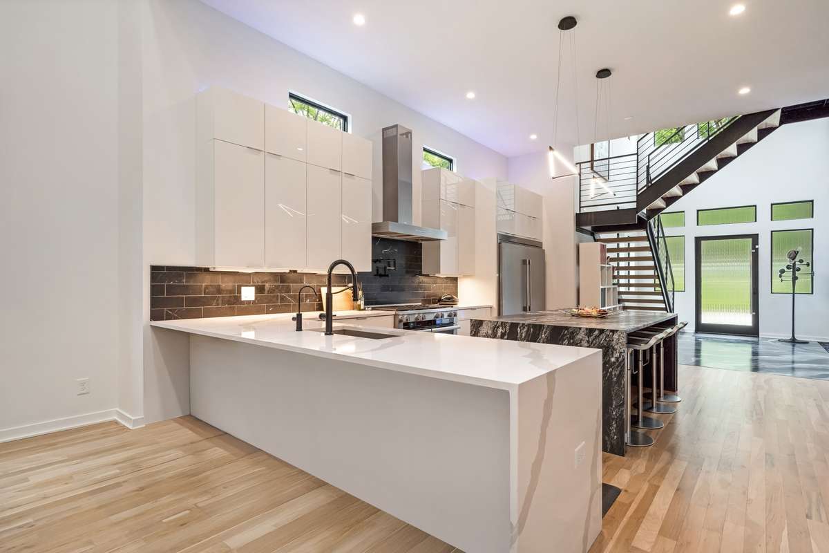 The perimeter quartz countertops feature a striking waterfall edge, complemented by ample room for bar seating. Above the cabinets, programmable accent lighting offers a range of colors to suit any mood or occasion