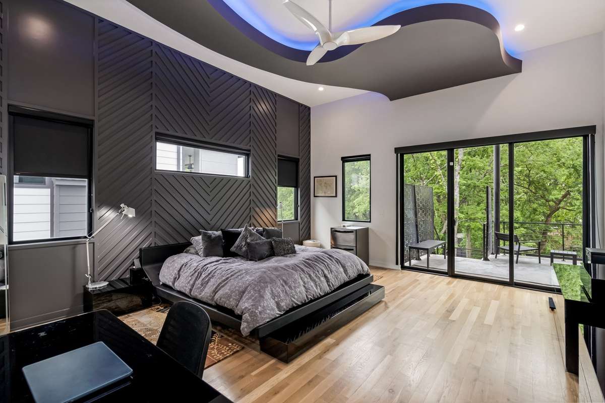 The luxury living continues in the primary suite, featuring a stylish backlit ceiling treatment with programmable multi-color lighting, along with patio doors that lead directly to the covered porch.