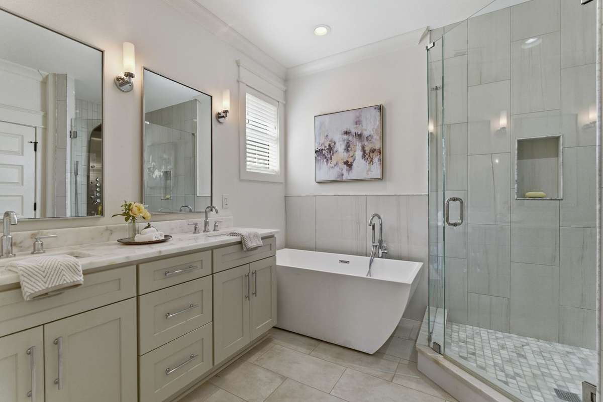 Luxurious primary bathroom featuring dual vanities, a relaxing soaking tub, and a walk-in shower.