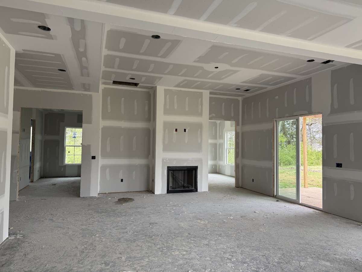 Living room will feature faux wood beams on ceiling, shelves & cabinet to left of fireplace, and shiplap boards with floating mantle on fireplace.
