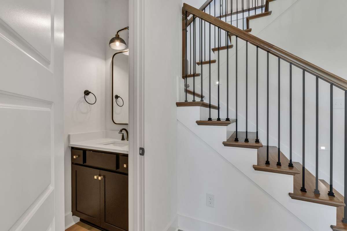 Photo of a previous built Ensley home. Shown for illustration purposes only. Materials and finishes will vary. Half bath located on main level. Black cabinet with white quartz.