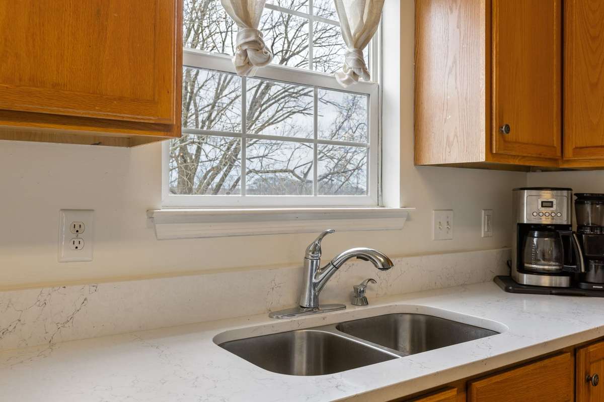 Double sink with window overlooking treetops. New quartz countertops.