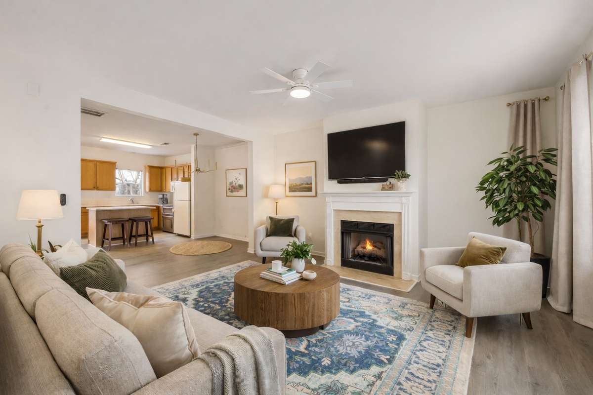 Inviting living room space with a gas-log fireplace, luxury vinyl plank flooring, lots of natural light, and an open floor plan. (Virtually staged.)