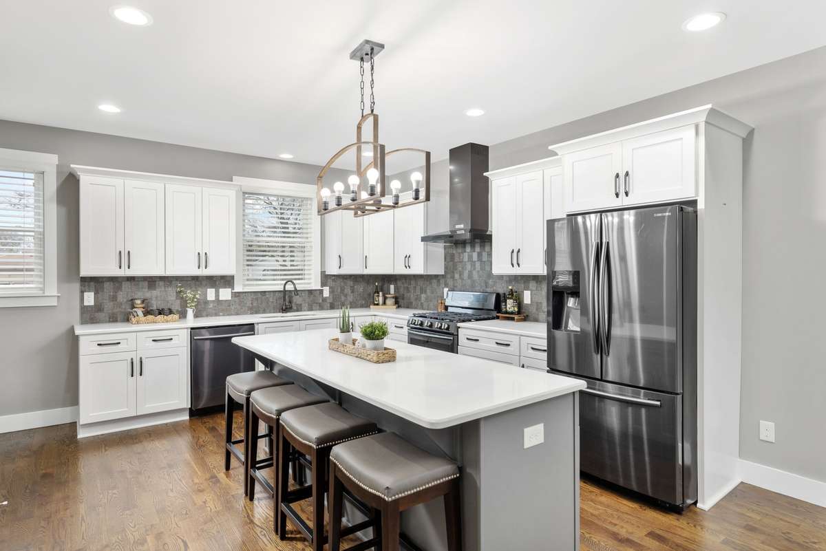 Stylish kitchen featuring a large island with seating, stainless steel appliances, and a sleek vent hood. Modern lighting and abundant cabinetry create a functional and inviting space for cooking and gathering.