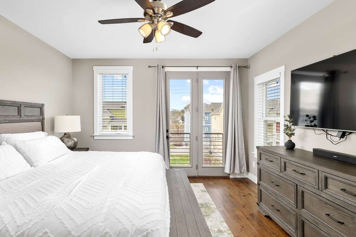 Spacious primary suite featuring hardwood floors, abundant natural light, and private balcony access through French doors. A comfortable retreat with modern finishes and a peaceful atmosphere.