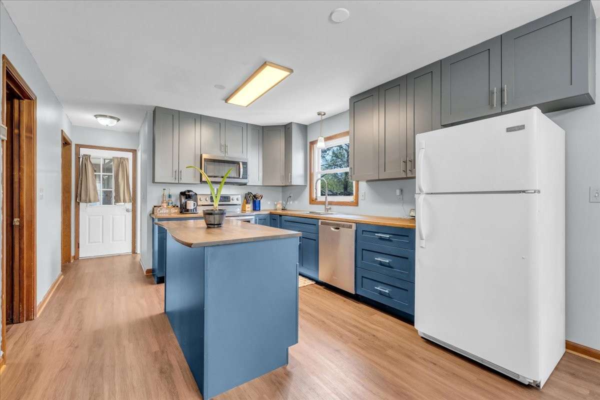 Updated kitchen featuring custom island, butcher block countertops, double oven, and additional built-in cabinetry with spacious dine-in area.