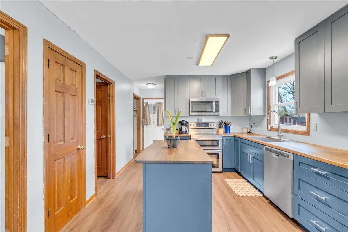 Updated kitchen featuring custom island, butcher block countertops, double oven, and additional built-in cabinetry with spacious dine-in area.