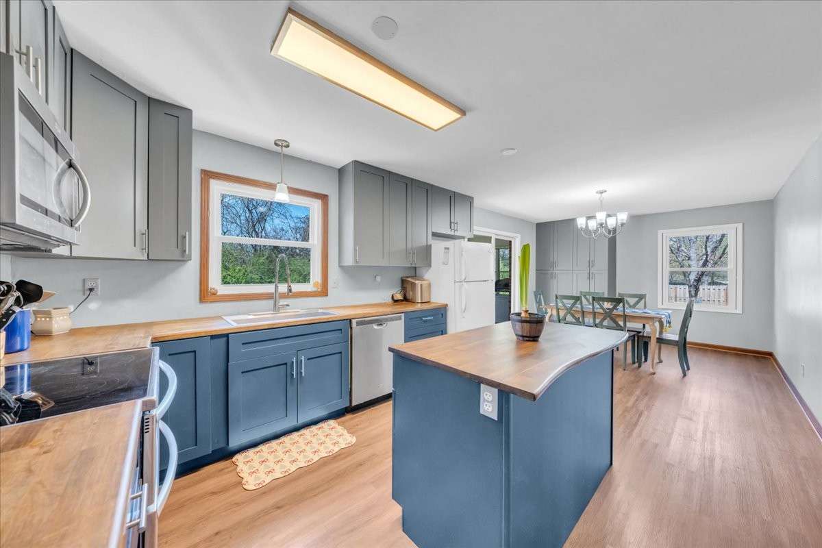 Updated kitchen featuring custom island, butcher block countertops, double oven, and additional built-in cabinetry with spacious dine-in area.
