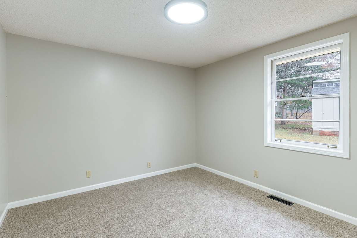 Bedroom 3 located in the rear of the home with a generously sized window brings in natural light and offers a pleasant view of the outdoors.