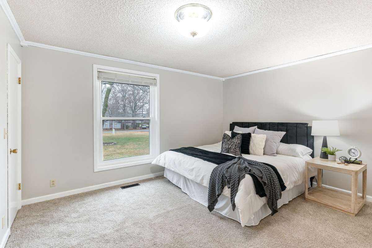The inviting primary bedroom offers a bright, serene atmosphere with its large picture window overlooking the spacious front yard