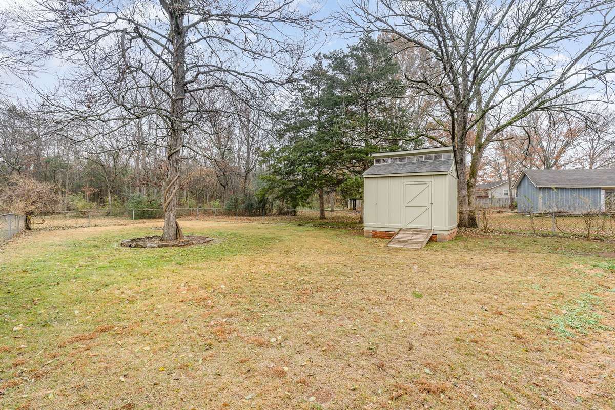 The Spacious fenced Backyard offers mature trees, plenty of open green space and a convenient storage shed--perfect for outdoor living and hobbies