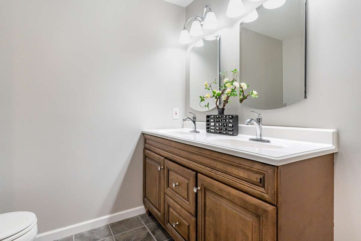 The en-suite primary bathroom features a spacious double-sink vanity with rich wood cabinetry offering plenty of storage and a warm, classic look.