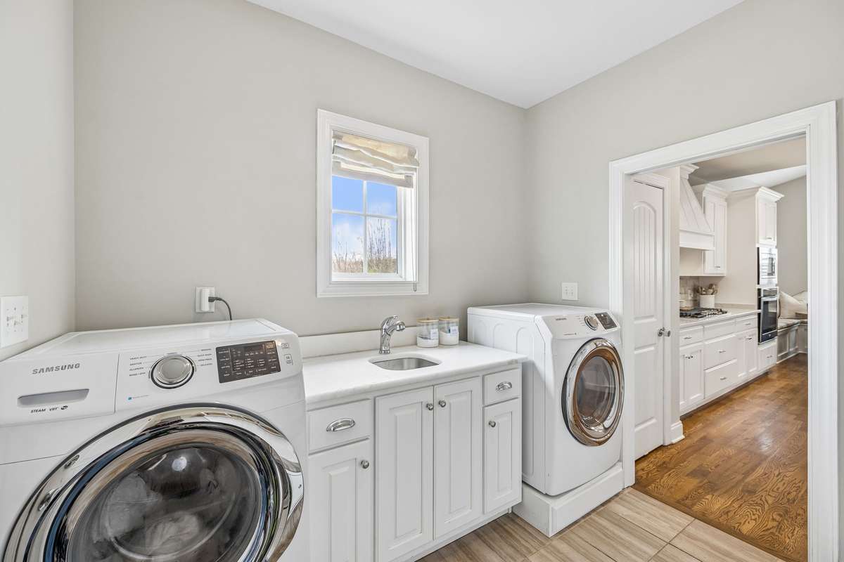 Laundry room & drop zone.  Located as you walk in from the garage. Sink with marble countertop.  Cabinets for extra storage.  Washer & dryer convey with home
