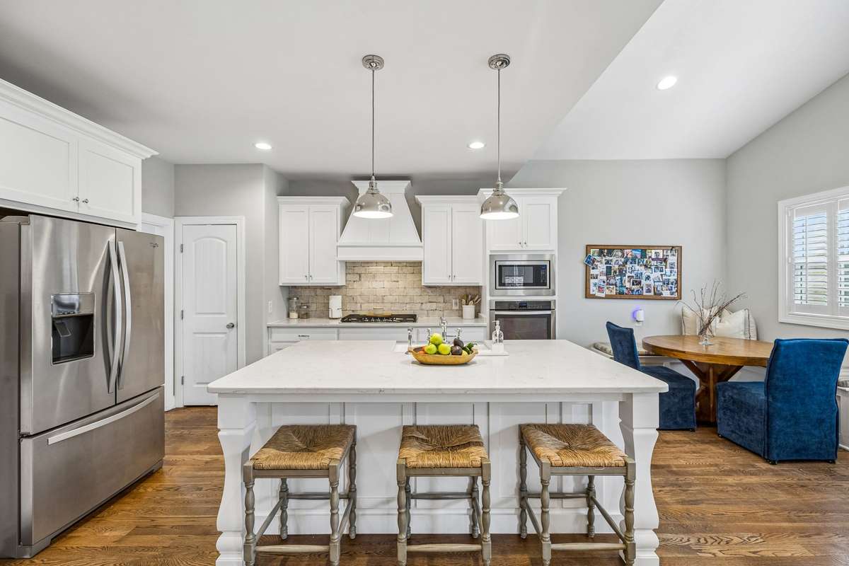 Gorgeous kitchen with large island, freshly painted cabinets, quartz countertops, pantry and vent hood. Stainless steel kitchen refrigerator conveys with home