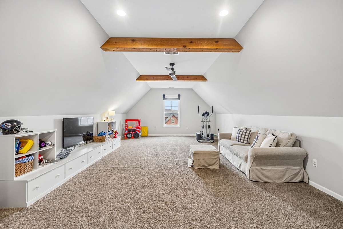 Large bonus room with wood beams and ceiling fan.  Bonus room provide extra storage with a closet and walk in attic.
