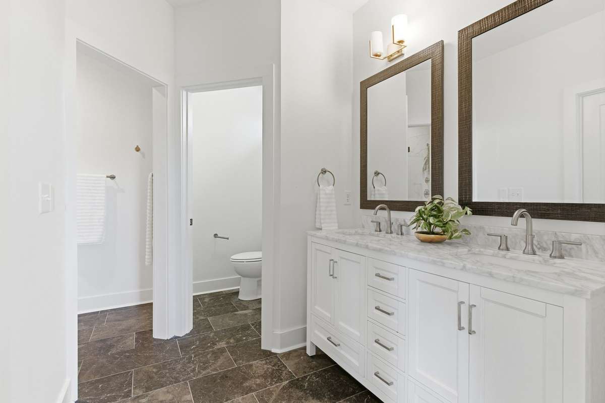 Spacious primary ensuite featuring double vanities, a private toilet closet, a separate shower room, and a walk-in closet.