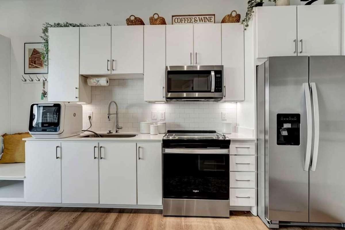 The kitchen is equipped with stainless steel appliances, ample cabinetry, and a tabletop dishwasher.