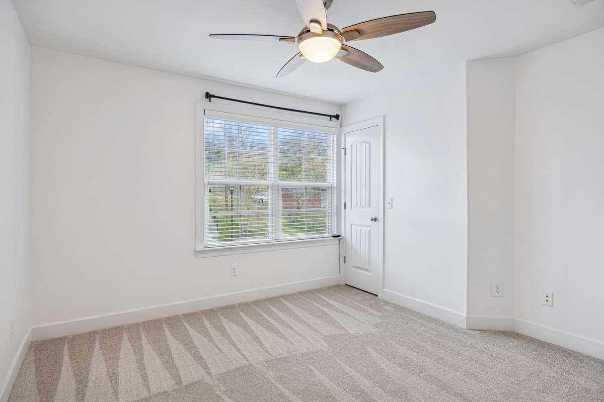 Secondary bedroom angle showcasing the closet and comfortable layout, complemented by natural light from the front-facing window.