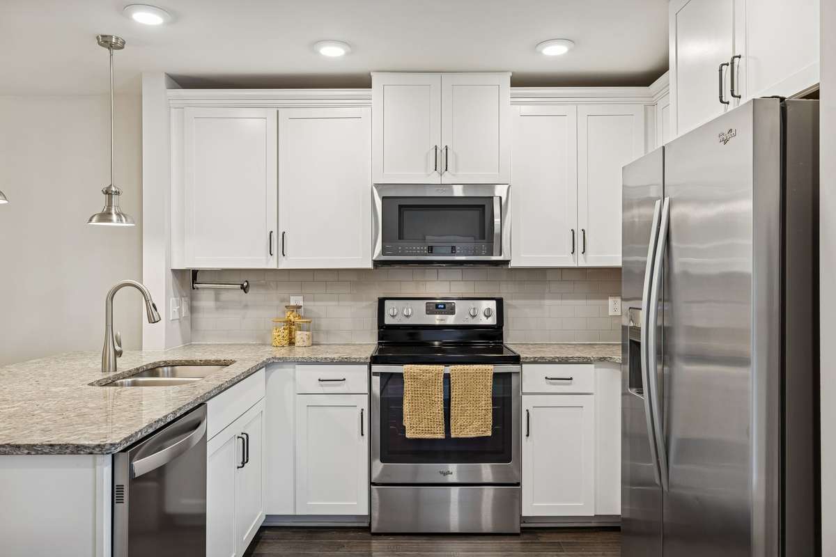 Bright kitchen with white cabinetry offering ample storage and clean, modern lines. A spacious pantry sits directly across from this area for added convenience.