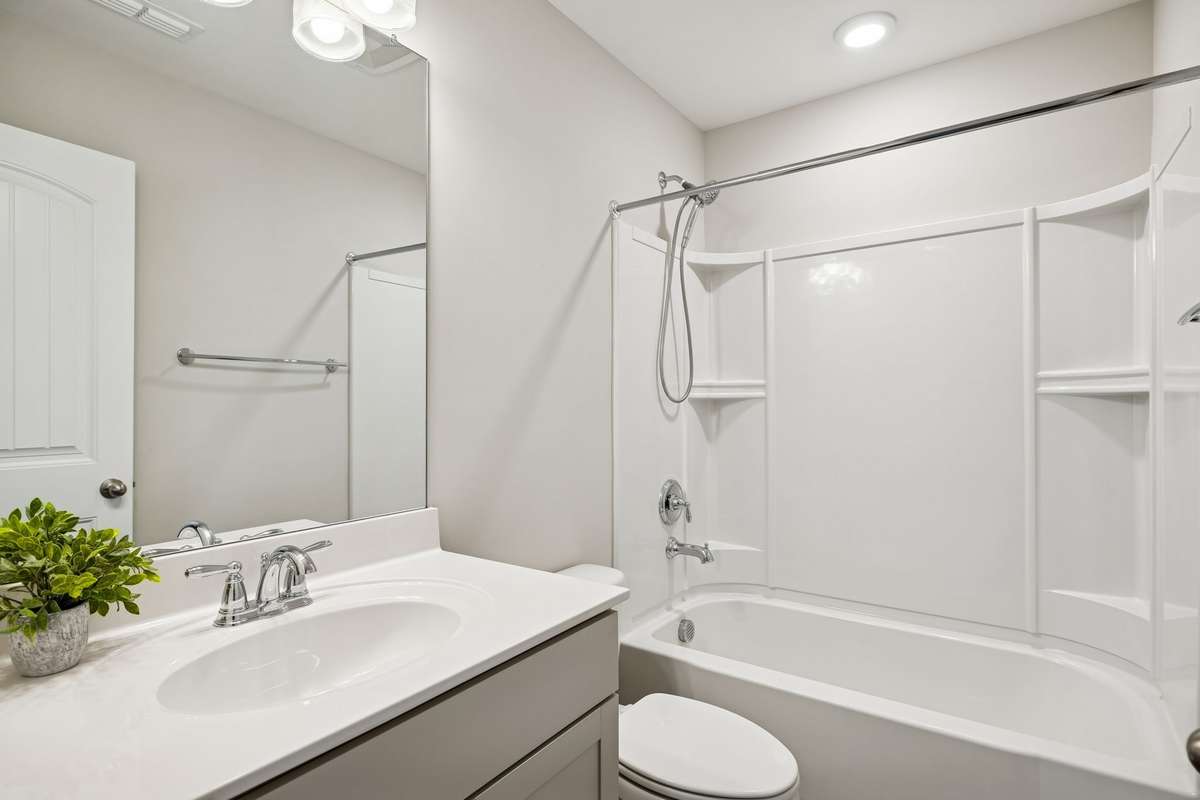 Secondary en-suite bathroom featuring a tub/shower combo and neutral, easy-to-maintain finishes.