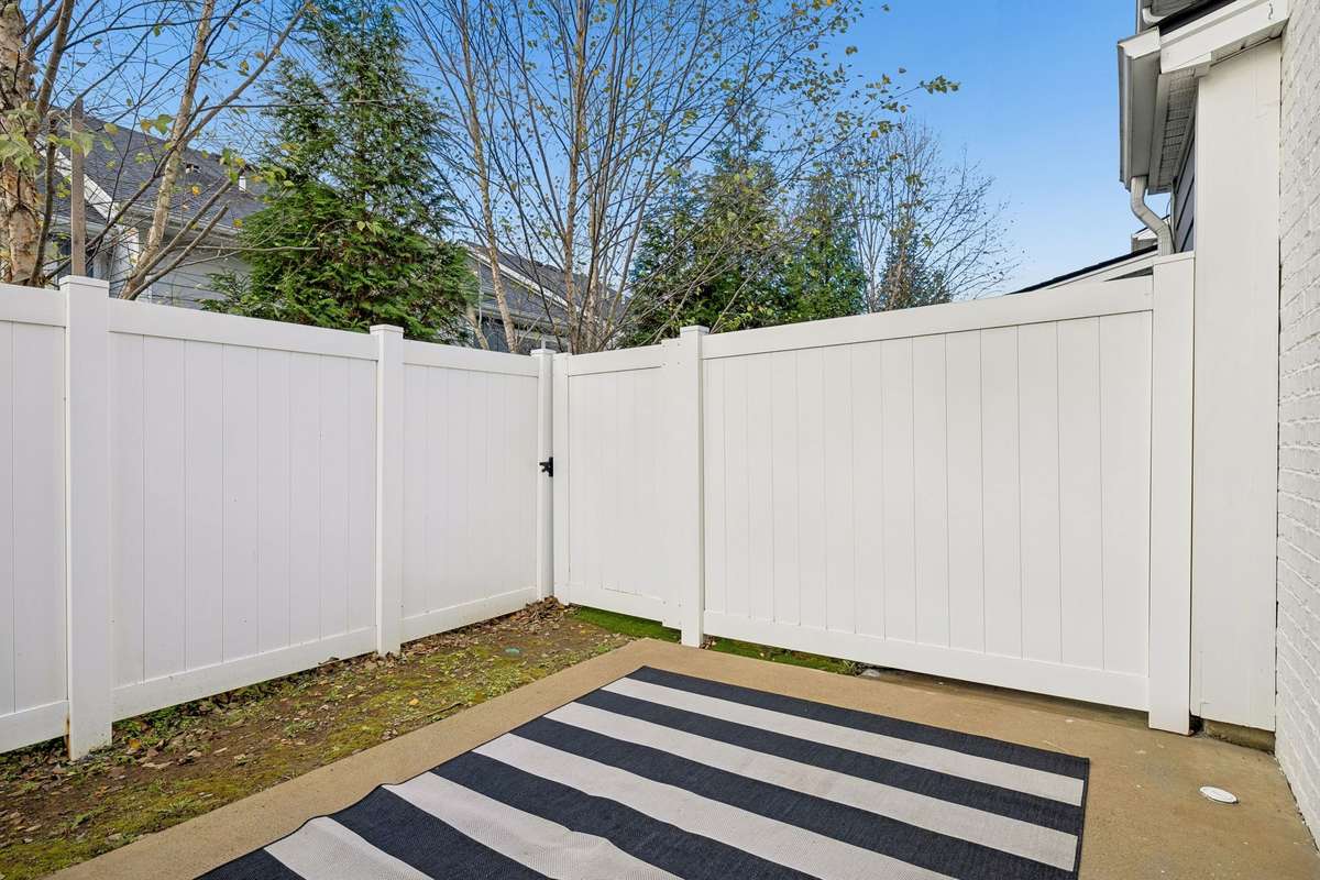 Back patio featuring a custom-sized outdoor rug that can remain with an acceptable offer, adding comfort and style to this private, fenced outdoor space.