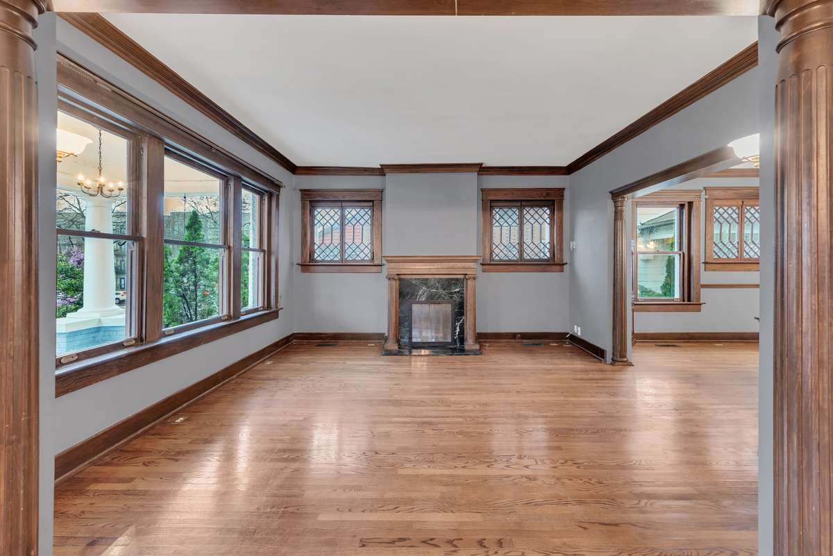 A  Spacious Living Room Highlighted by Hardwood Floors, Original Woodwork and Fireplace